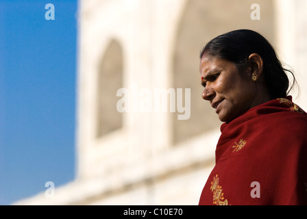 Ritratto di una donna Indiana guardando in giù con il Taj Mahal di parete in background e incredibile cielo blu Foto Stock