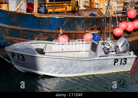 Piccola barca di alluminio legato al fianco di un vecchio arrugginito barca da pesca nel Dock di campanatura, Portsmouth. Foto Stock