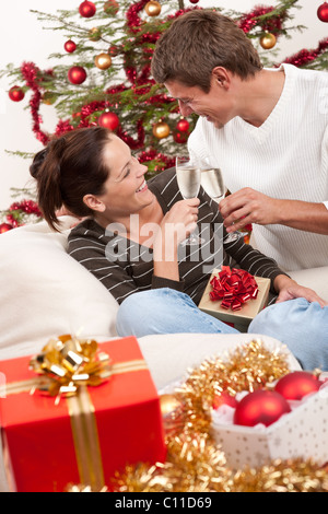 Coppia giovane con un bicchiere di champagne nella parte anteriore dell albero di Natale Foto Stock