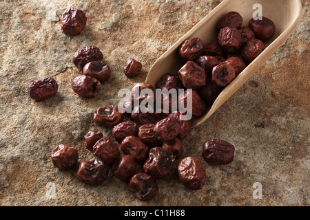 Jujuba bacche (Ziziphus jujuba) con una pala di legno sulla superficie di pietra Foto Stock