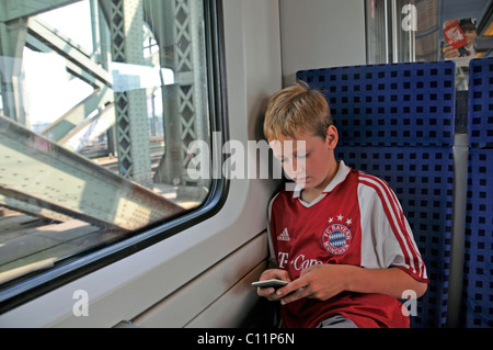 Otto-anno-vecchio ragazzo seduto da solo in un treno locale e giocando, Germania, Europa Foto Stock