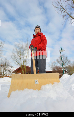 Donna spalare la neve dal marciapiede Foto Stock