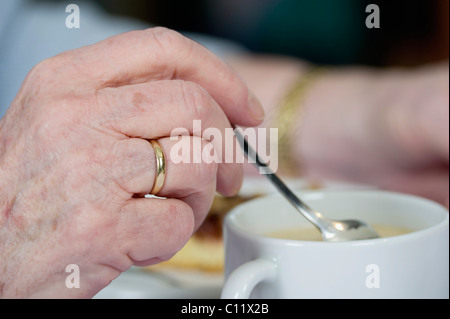 Il vecchio donna agitazione a mano in una tazza di caffè, Germania, Europa Foto Stock