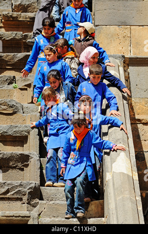 I bambini di una scuola classin uniformi scolastiche, teatro romano di Bosra, Siria, Asia Foto Stock