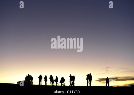 Silhouette di persone e fotografi in montagna all'alba. Sagome di persone contro il cielo di notte. Dopo un declino. Foto Stock