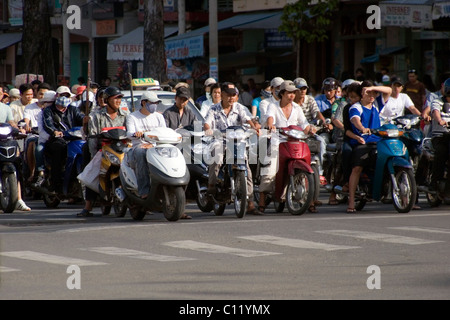 Persone che guidano motocicli sono in attesa in corrispondenza di una intersezione su una rumorosa e affollata strada di Saigon (Ho Chi Minh City) Vietnam. Foto Stock