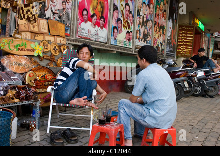 Due uomini sono di bere il caffè a venditori di souvenir sostare vicino Vinh Quang Theatre di Saigon (Ho Chi Minh City) Vietnam. Foto Stock