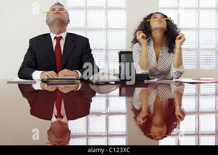Imprenditore annoiato e segretario giocando con matita e divertirsi in office sala riunioni. Foto Stock