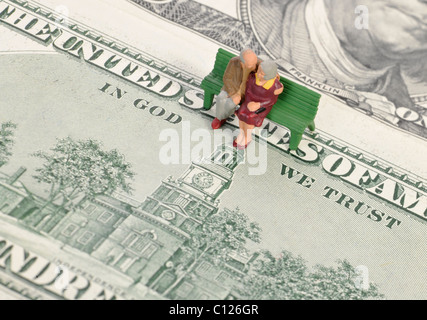 Titolare di pensione o di rendita figure in miniatura su 100-fatture del dollaro, il motto In God We Trust, immagine simbolica per la pensione, disposizioni di pensionamento Foto Stock