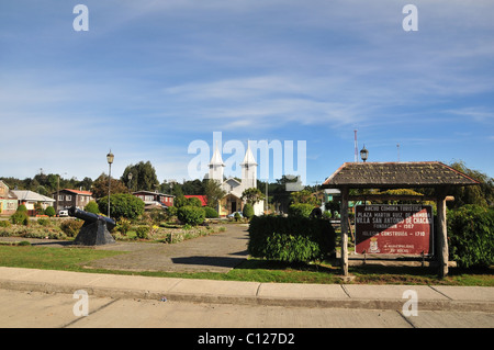 Cielo blu vista di Plaza Martin Ruiz, con informazioni segno, cannone nero e Silver e chiesa di San Antonio, Chacao, Chiloe, Cile Foto Stock