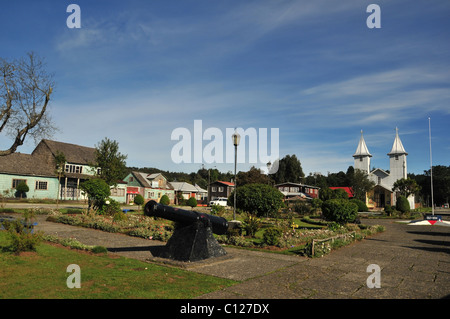 Sunny View di Plaza Martin Ruiz, con cannone nero, verde shingle edifici color argento e la chiesa di San Antonio, Chacao, Chiloe, Cile Foto Stock