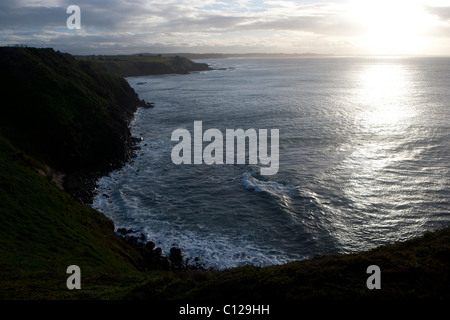 Coastal cliff volti in silhouette e l'oceano che mostra azione di marea riflessa con inizio giorno solare. Circuito australiano di Phillip Island. Foto Stock