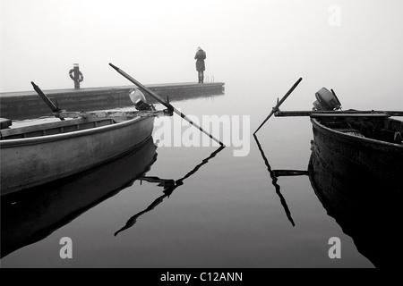 Un solitario lady sul bordo di un piccolo molo su Aghios Achilleios isolotto in Mikri Prespa Lake, Florina, Macedonia, Grecia. Foto Stock