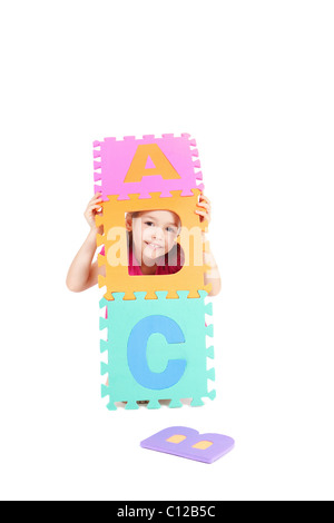 Ragazza giovane giocando ABC alfabeto lettere. Isolato su bianco. Foto Stock