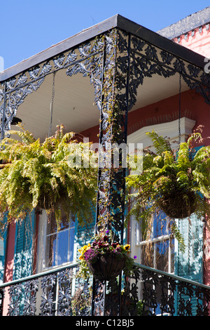 Ornati in ferro battuto balcone con le piantatrici appeso nel Quartiere Francese di New Orleans, Louisiana Foto Stock