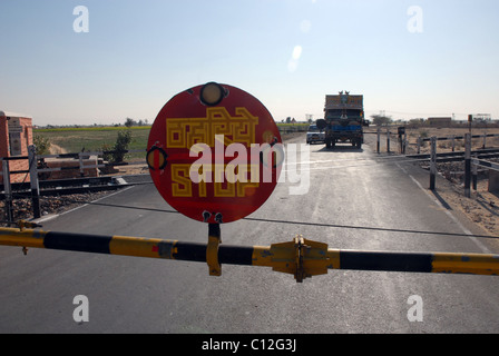 Autocarro, carrello a livello di attraversamento con segno di stop in Rajasthan, India Foto Stock