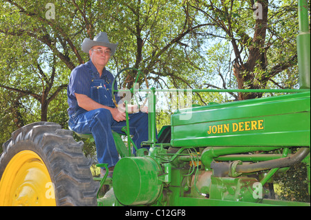 Un nuovo Messico rancher siede orgoglioso sul suo luminoso verde-trattore John Deere in Capitan, Nuovo Messico. Foto Stock