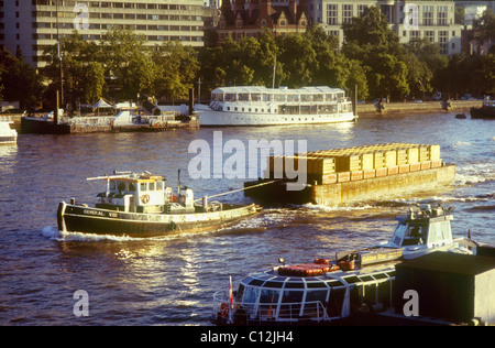 Rimorchiatore a traino e spazzatura chiatta a monte di viaggio sul fiume Tamigi vicino a Hungerford Bridge Foto Stock