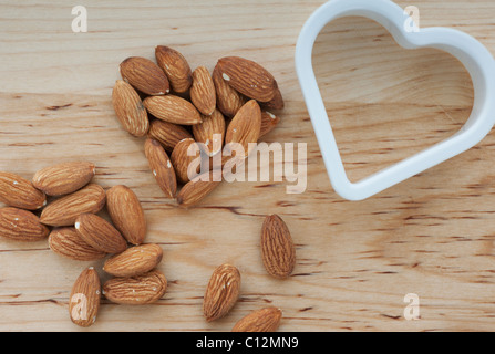 A forma di cuore le mandorle con fresa sul tagliere Foto Stock