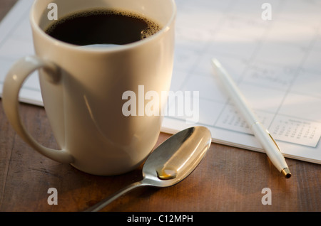 Tazza di caffè accanto al calendario Foto Stock