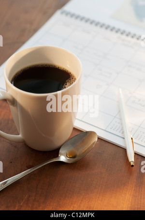 Tazza di caffè accanto al calendario Foto Stock