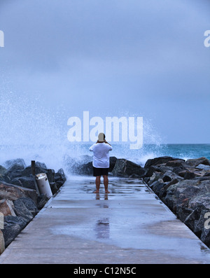 L'uomo prendendo fotografie delle onde provenienti da groyne. Le grandi onde sono stati provocati dal ciclone Bianca Foto Stock