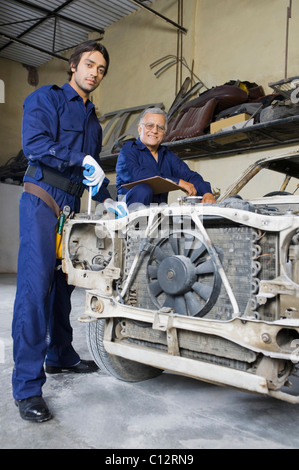 Auto meccanico con un apprendista di riparazione di un auto in un garage Foto Stock