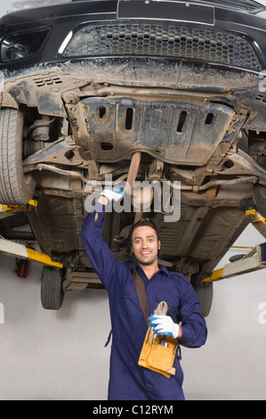 Meccanico automatico di lavorare sotto un rilievo auto in un garage Foto Stock