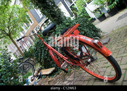 Bicicletta rossa sotto agli alberi in Amsterdam, Olanda Foto Stock