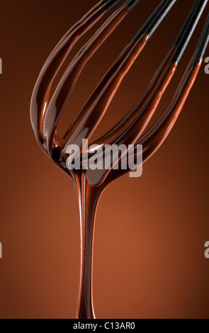 Cioccolato fondente il gocciolamento da una frusta Foto Stock