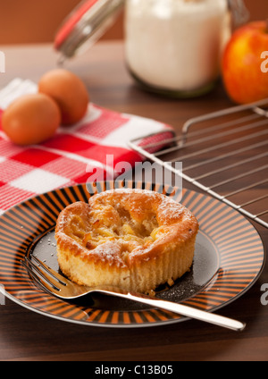 Piccola casa apple la torta su un piatto circondato da ingredienti Foto Stock