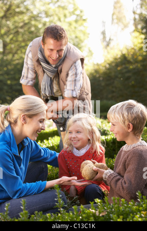 Famiglia giovane sedersi insieme in giardino Foto Stock