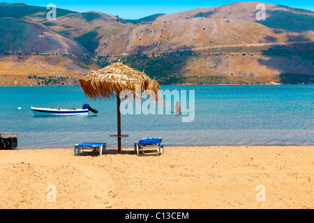 Spiaggia e lettini su Agrostoli baia vicino a Lixouri, CEFALLONIA, ISOLE IONIE, Grecia. Foto Stock