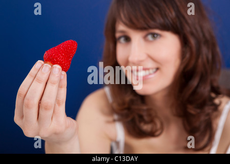 Bella giovane donna holding e mostrando una grande e fragole fresche Foto Stock