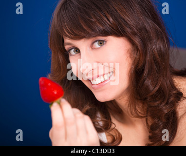 Bella giovane donna holding e mostrando una grande e fragole fresche Foto Stock