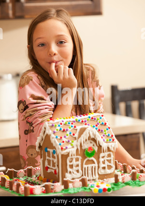 Stati Uniti d'America, Utah, Lehi, ritratto di una ragazza (6-7) leccare il dito da gingerbread house Foto Stock