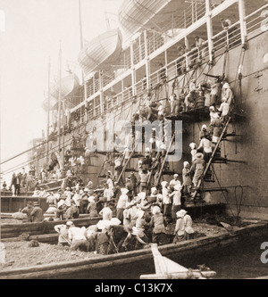 Stazione di rivestimento a Nagasaki, in Giappone. Giovani uomini e donne su chiatte e ponteggi formano una brigata di benna, passando il carbone fino al lato della nave posta durante il rifornimento di carburante. Navale e le flotte mercantili erano dipendenti su tali strutture strategiche. Maggio 1904. Foto Stock