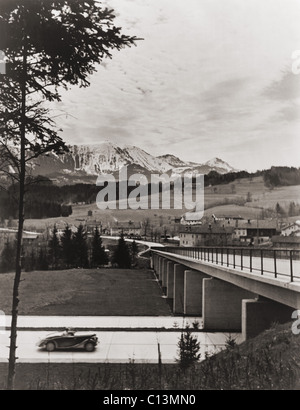 Automobile avvicinando cavalcavia sulla autostrada tedesca con la campagna e le montagne sullo sfondo. Ca. 1938. LC-USZ62-128819 Foto Stock