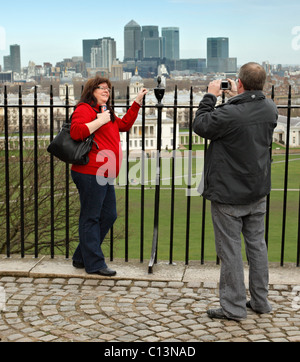 I turisti che posano per una foto di fronte a Canary Wharf, Londra. Foto Stock