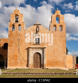 La facciata anteriore della chiesa francescana di Mani square. Adobe ocra, una massiccia porta di legno e uno di lavoro campanile domina Foto Stock