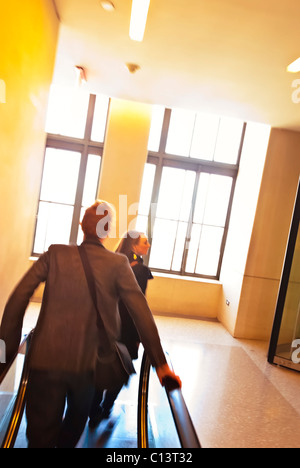 FEB. 27, 2011 - NEW YORK - motion blur, inclinato vista da dietro del giovane uomo e donna, equitazione fino escalator a 30 Rockefeller Center Foto Stock
