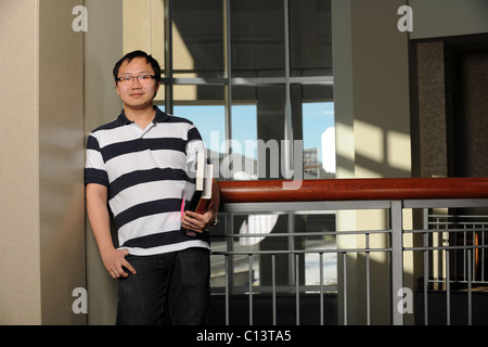 Ritratto di sorridente studente asiatico con libri in ambienti interni Foto Stock