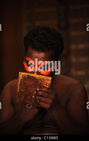 Uomo di applicare il make-up per il Kathakali prestazioni, Kochi, Kerala, India Foto Stock