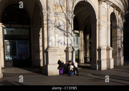 Un sonno grande problema magazine venditore si siede da solo senza passare business a Londra in Trafalgar Square. Foto Stock