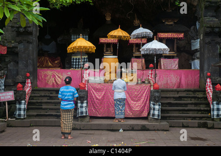 Due donne fanno offerte all'altare nel tempio della grotta dei pipistrelli di 1000 anni, chiamato pura Goa Lawah a Klungkung, Bali orientale vicino a Padang Bai Foto Stock