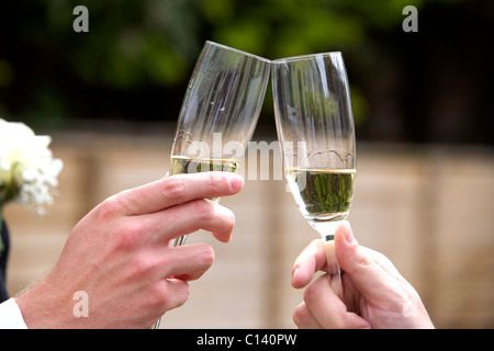 Due mani unendo i bicchieri di champagne in festa Foto Stock