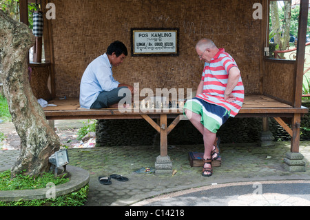 Anziani touriust giocando una partita amichevole di scacchi con un locale in Ubud, Bali, Indonesia Foto Stock