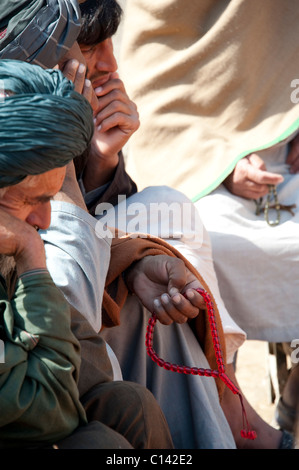 Gli uomini in Helmand con grani di preghiera Foto Stock