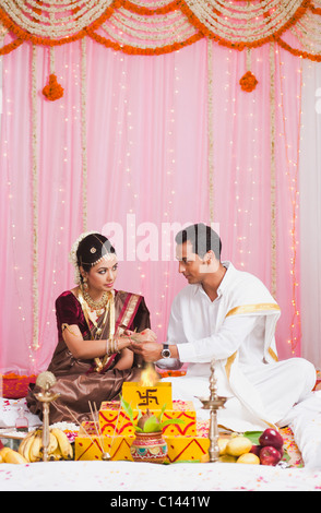 Sposo mettendo santo filettatura su una sposa del polso Foto Stock