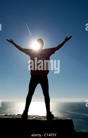 Silhouette di un atleta maschio dal mare fino a raggiungere il cielo Foto Stock